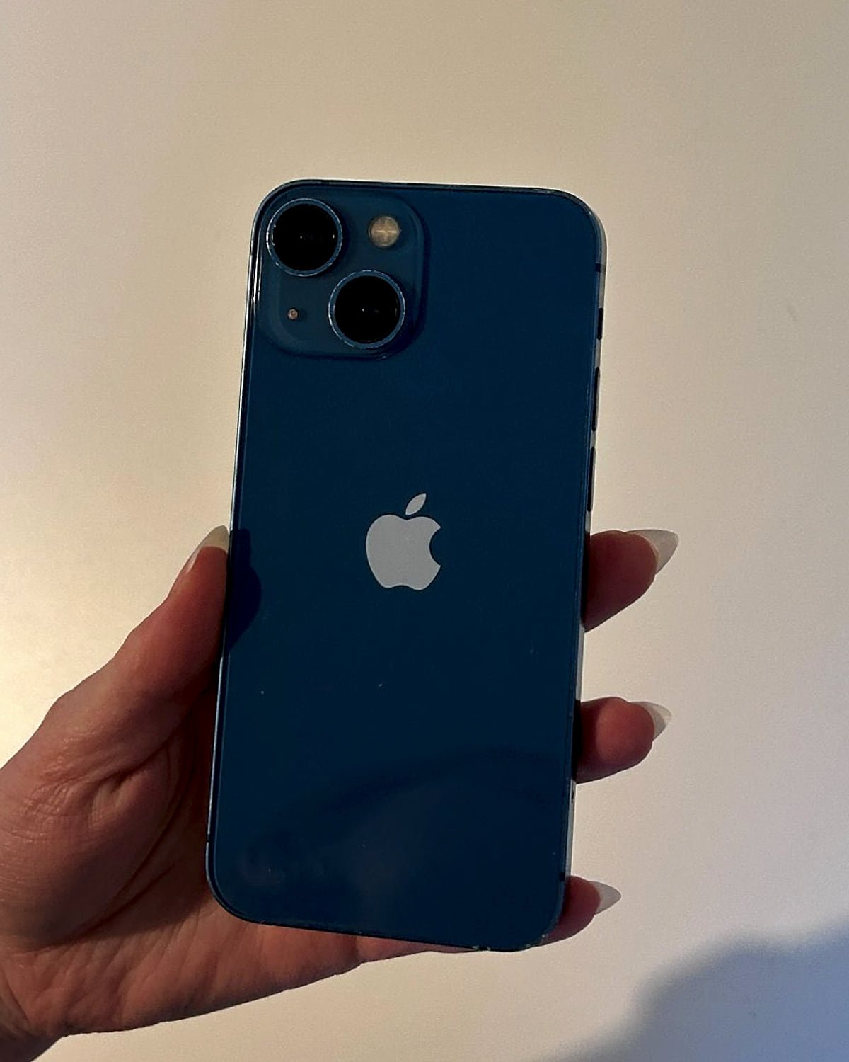 iPhone 13 in blue, held up to show the back