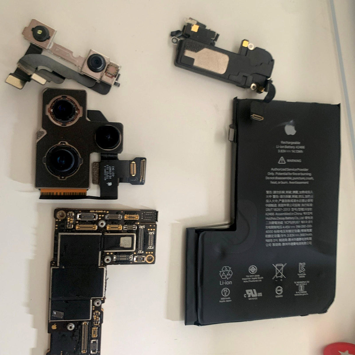 An iPhone logic board, battery and camera modules on the bench