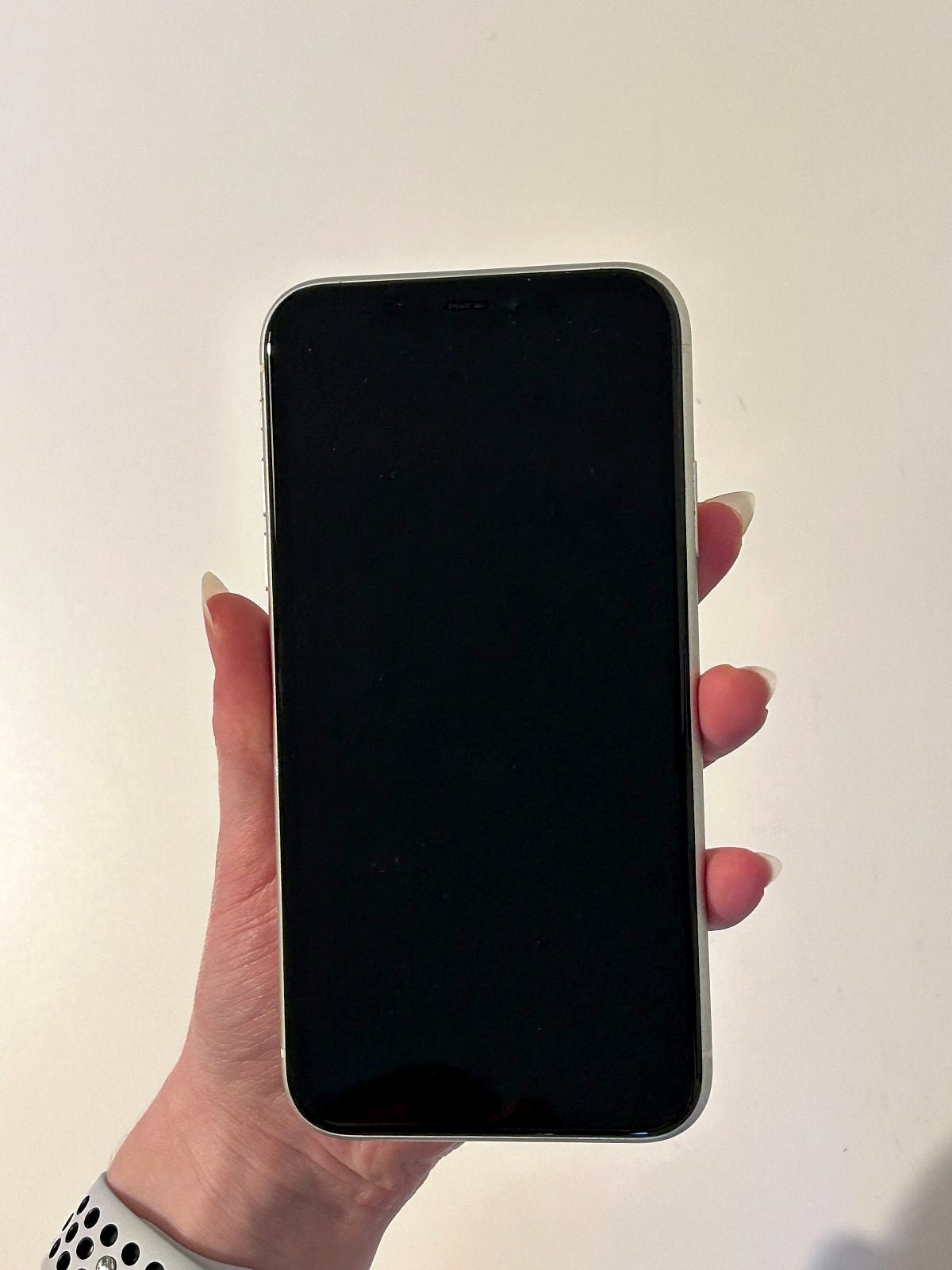 An iPhone with a black screen, held in a hand