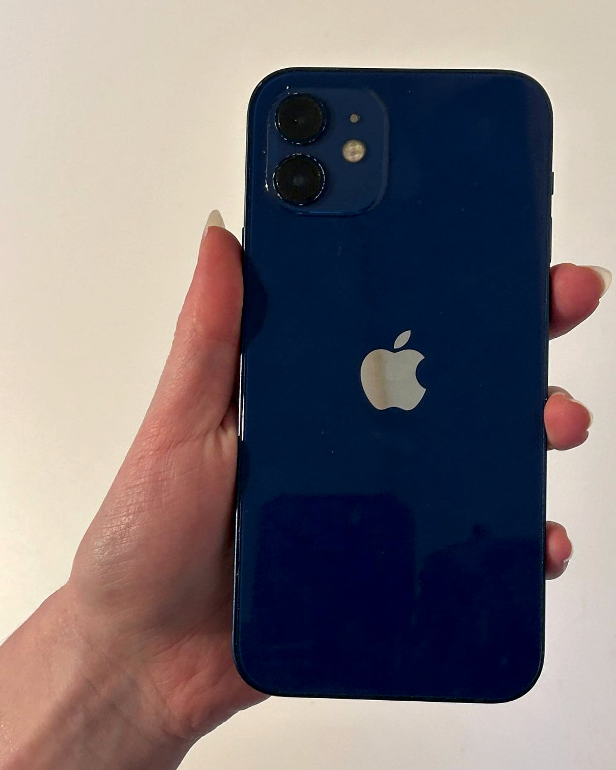 iPhone 12 in blue, held up to show the back