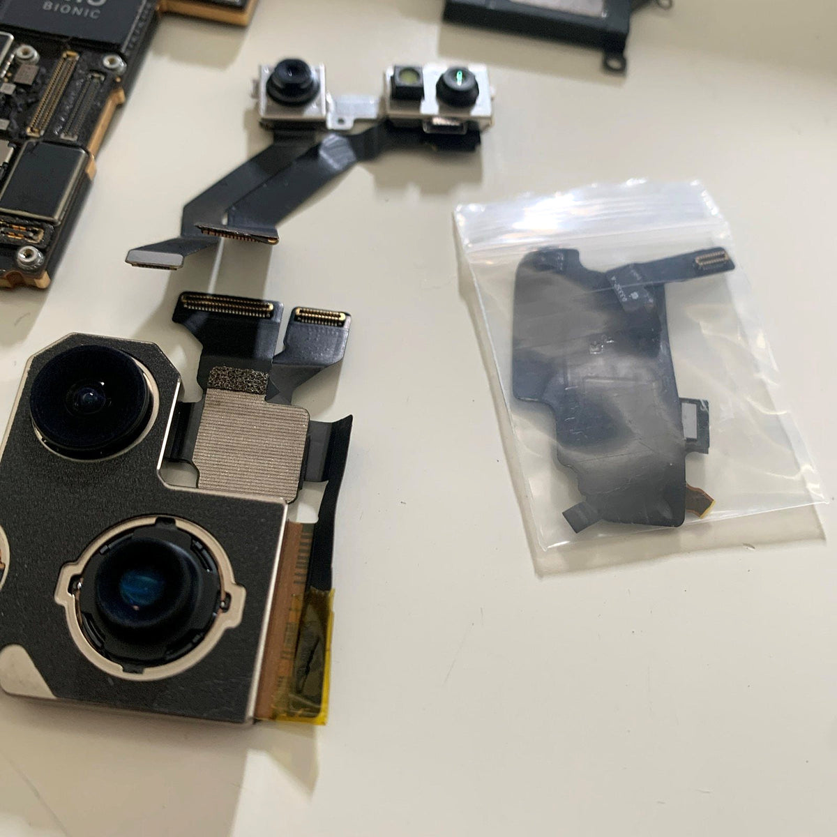 iPhone rear camera modules and a front camera flex on the bench