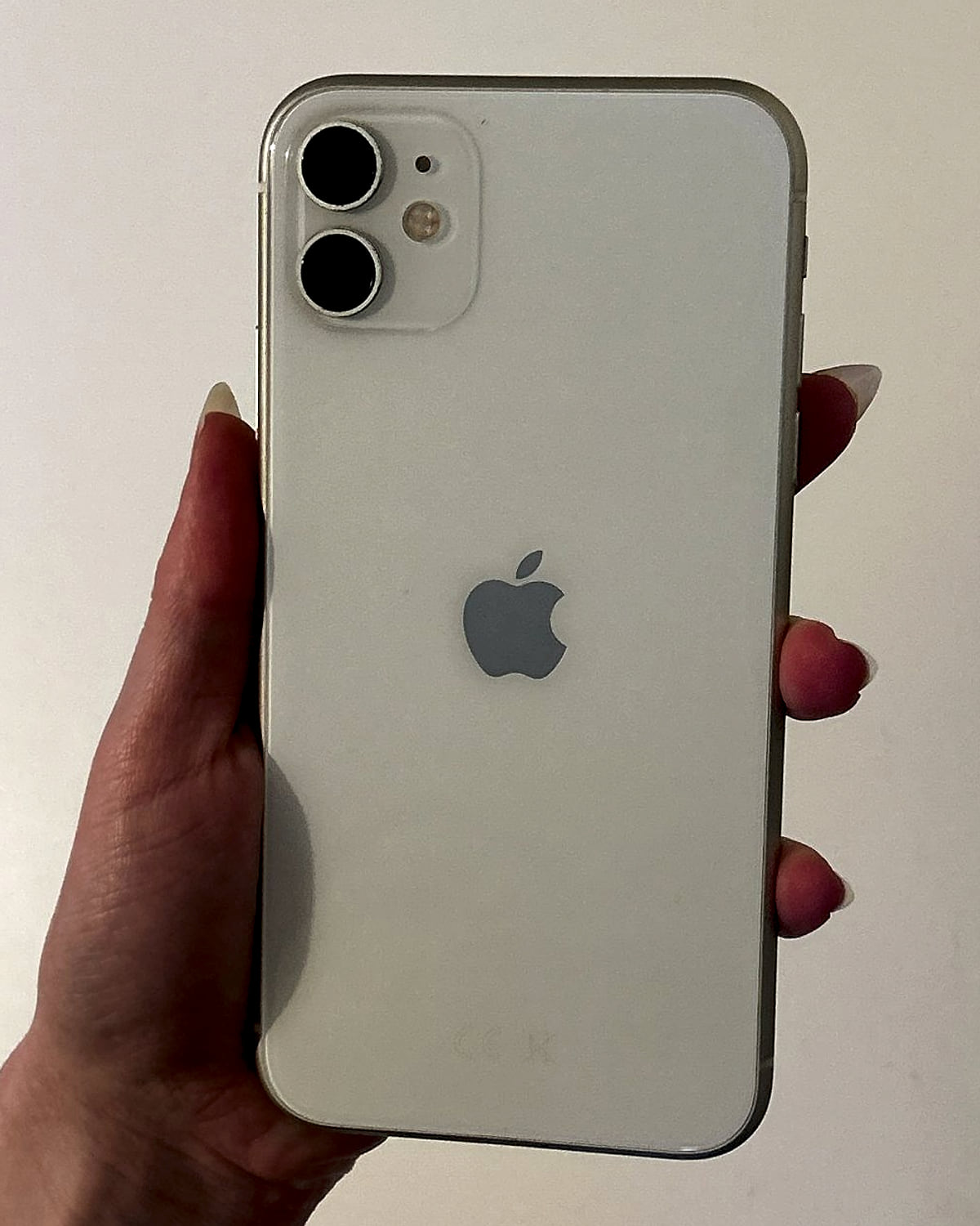 iPhone 11 in white, held up to show the back