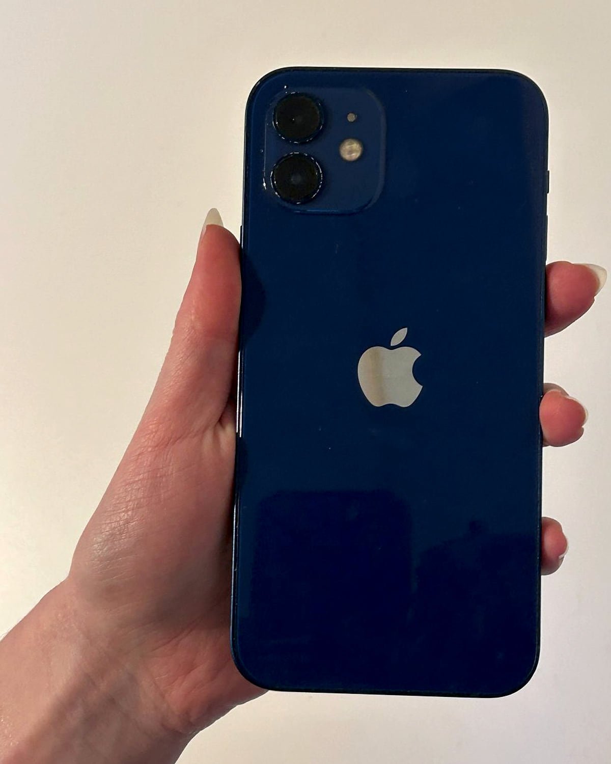 iPhone 12 in blue, held up to show the back